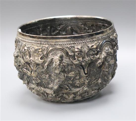 A 19th century Burmese embossed white metal bowl, decorated with figures and scrolls,